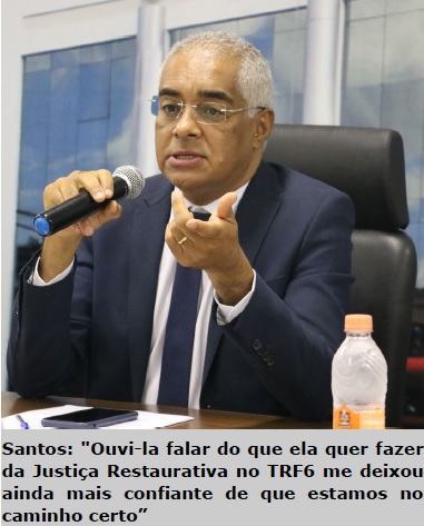 foto de perfil homem negro sentado em uma mesa falando ao microfone