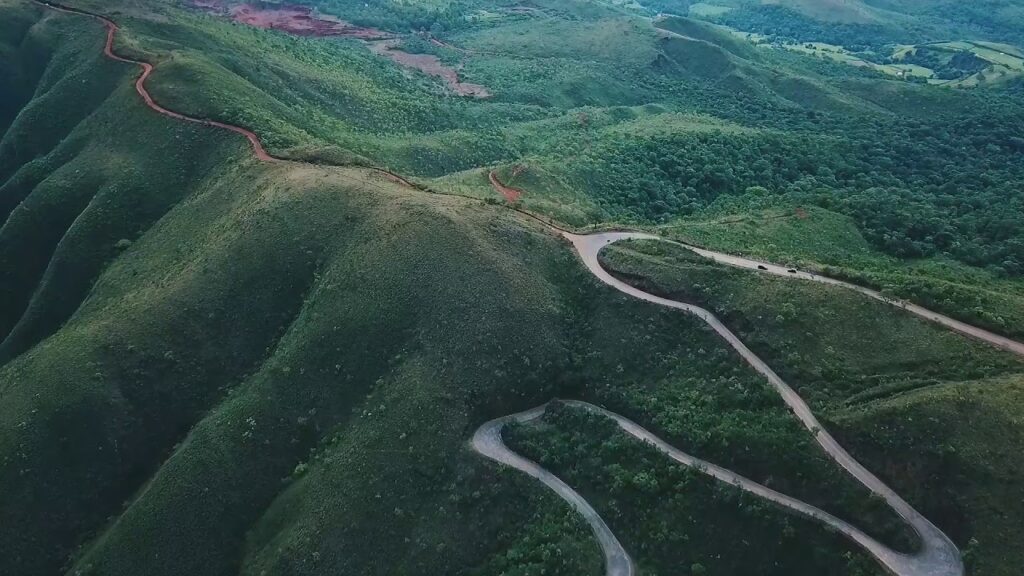 foto horizontal serra com vegetação bem verde e uma estrada passando no meio.