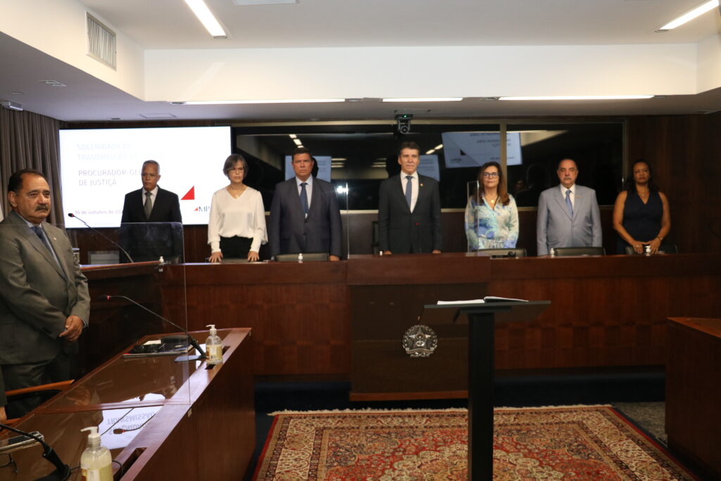 Fotografia horizontal colorida pessoas em pé atrás da mesa do evento