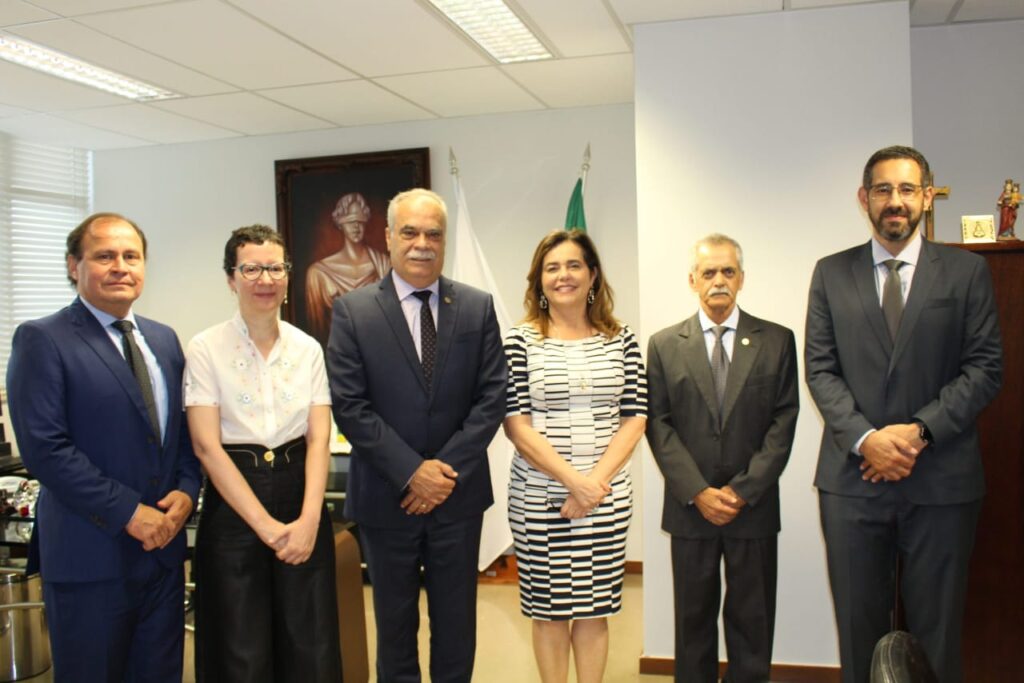 Fotografia horizontal colorida pessoas em pé lado a lado em um gabinete. Legenda: vice-presidente do TRF6, Vallisney de Souza Oliveira; juíza Daniela de Freitas Marques; presidente do TJMMG, Rúbio Paulino Coelho; presidente do TRF6, Mônica Sifuentes; corregedor do TJMMG, Sócrates Edgard dos Anjos e o juiz federal Ivanir Ireno Júnior