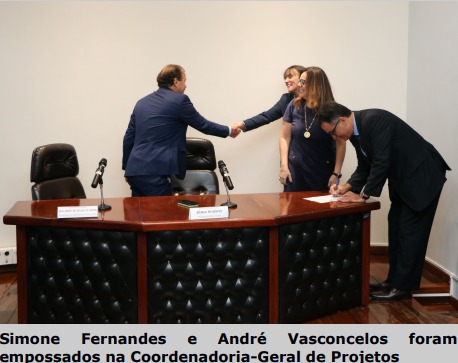 Fotografia horizontal colorida uma mulher e um homem se cumprimentado com aperto de mão uma pessoa assinando documento em cima da mesa. Legenda: Simone Fernandes e André Vasconcelos foram empossados na Coordenadoria-Geral de Projetos