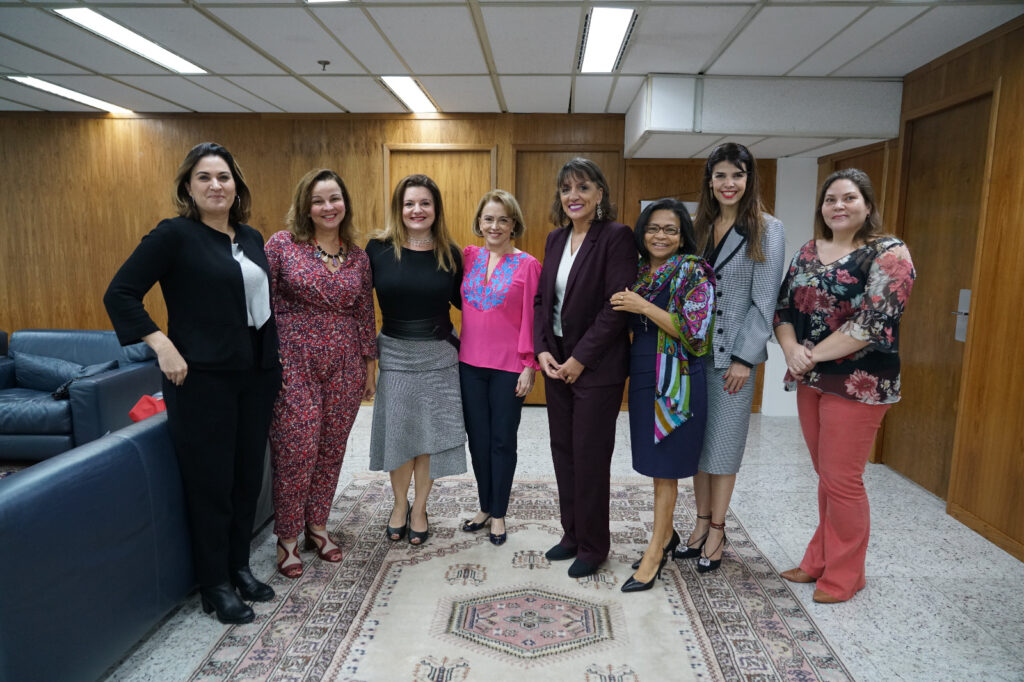 Fotografia retangular e colorida em que aparecem oito mulheres de pé.