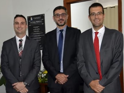 Fotografia colorida com três homens de terno e gravata lado a lado. Legenda: Juiz federal Lucílio Linhares Perdigão de Morais entre os juízes da Comarca de Abre Campo, Rodrigo Maas dos Anjos e Vinícius Pereira de Paula.