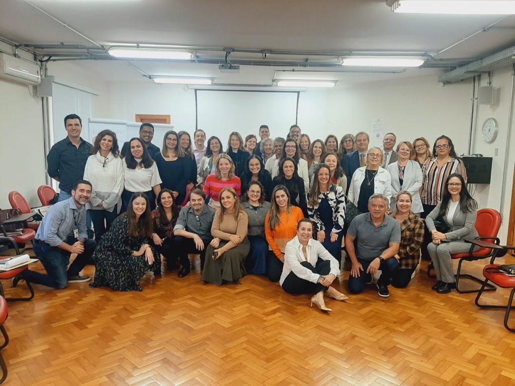 Fotografia colorida com vários magistrados e servidores posando para uma foto. Ao fundo, um quadro branco na parede. Legenda: Participantes do curso e equipe da Enfam.