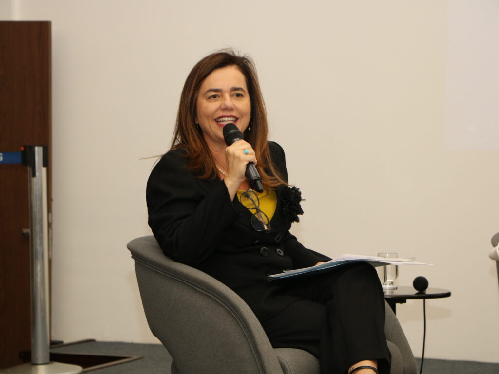 Fotografia colorida de uma mulher com trajes formais de cor preta falando ao microfone. Legenda: Desembargadora federal Mônica Sifuentes.