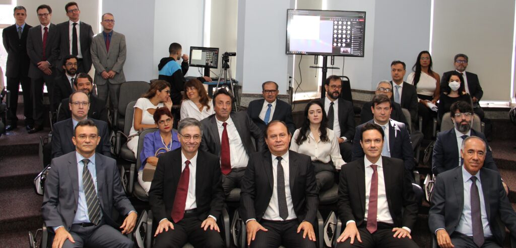 Fotografia colorida horizontal de um grupo de pessoas sentadas em um auditório.